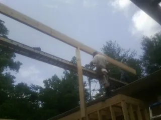 Carpenter setting a ridge beam over a new addition frame — Ice Dam Removal by Roofing Brothers in Deweyville