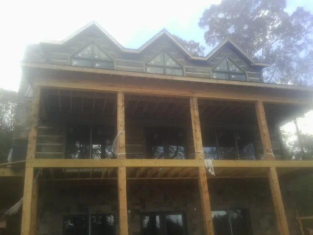 Dormers and porch framing on a large log home under construction — Roof Coating work by our crew in Deweyville