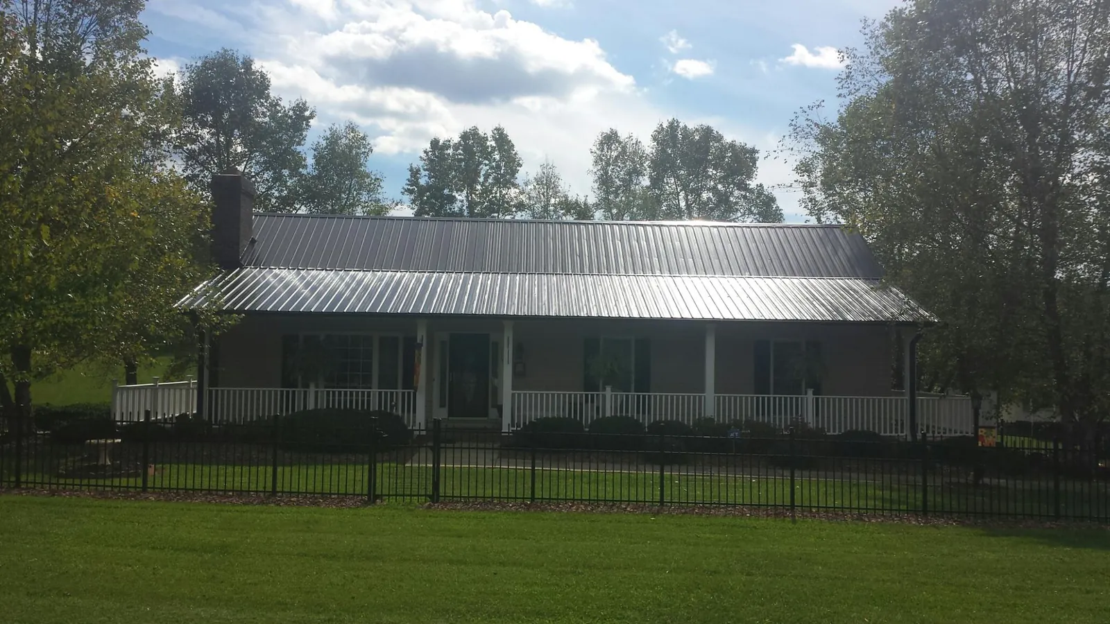 Gray metal roof on a brick ranch with a full width front porch — Gutter Guard Installation work by our crew in Deweyville