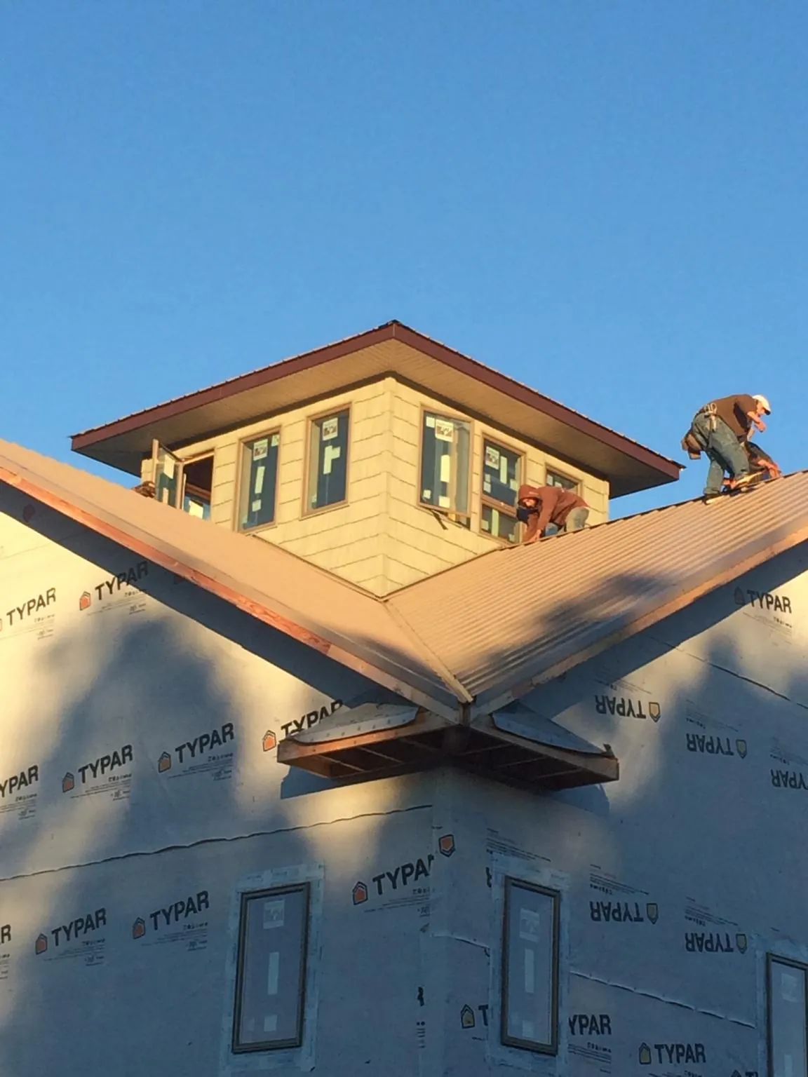 Roofers working around a rooftop cupola on a new metal roof at sunset — Roof Waterproofing in Deweyville by Roofing Brothers